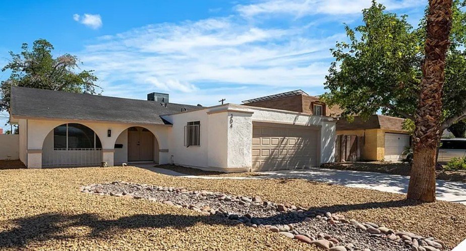 Single-story residential home featuring a gravel front yard and a driveway with a garage.