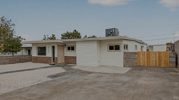 Single-story residential home with a fenced yard and gravel driveway.