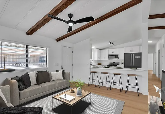 Contemporary living room featuring a sofa, coffee table, and a view of the kitchen area with bar stools.