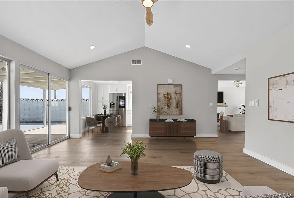 Bright remodeled living room in Las Vegas, NV with white walls, gray accents, and warm wood flooring, open layout with modern light fixtures.